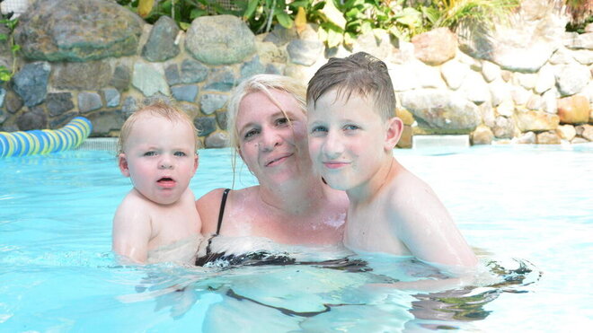 a woman in a swimming pool with her two sons